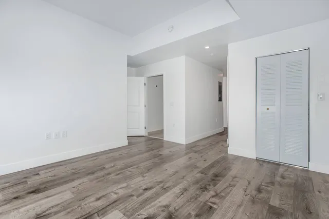 a view of an empty room with wooden floor and closet
