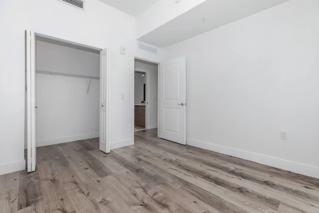 an empty room with wooden floor and closet