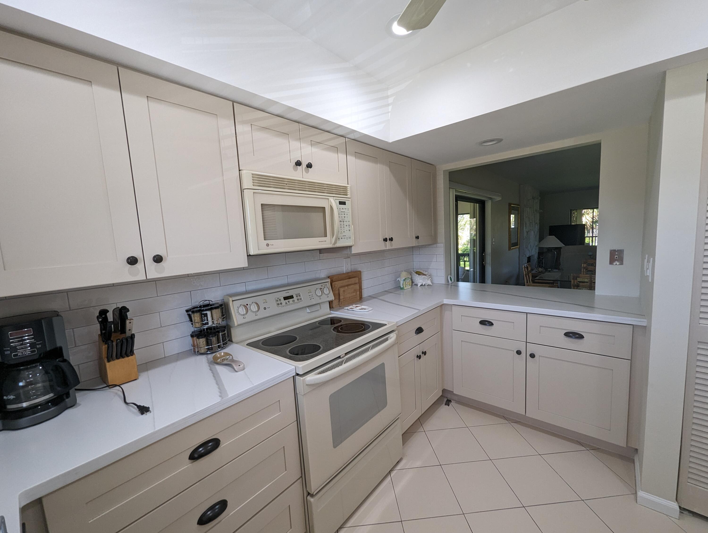 404 Clubhouse Circle Jupiter, FL 33477 - Photo 4 of 26 a kitchen with white cabinets and white appliances