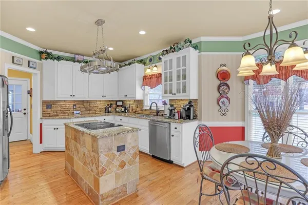 a kitchen with stainless steel appliances granite countertop a sink dishwasher and white cabinets with wooden floor