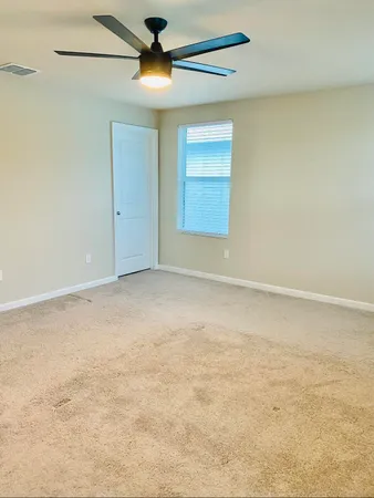 en empty room with windows and ceiling fan