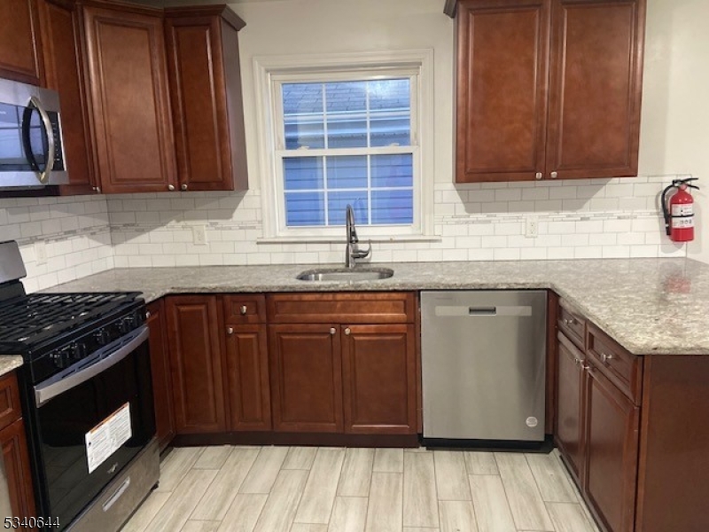 455 South 14th Street, Unit 3 Newark, NJ 07103 - Photo 3 of 10 a kitchen with granite countertop wooden cabinets a sink and a stove with wooden floor