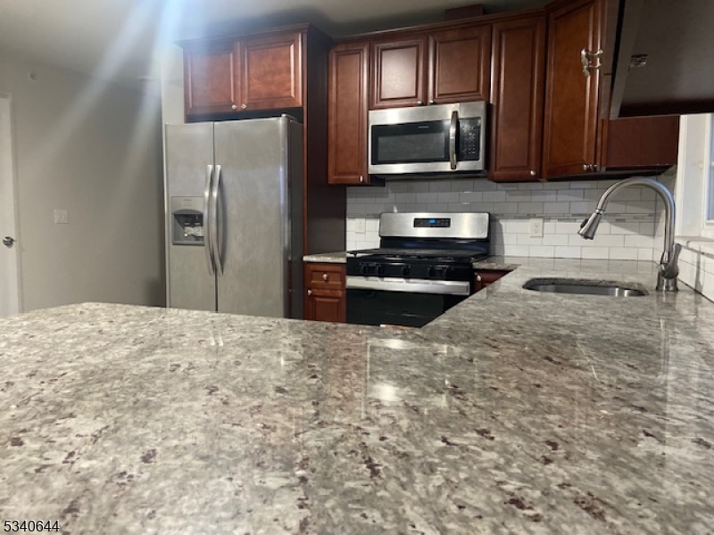 455 South 14th Street, Unit 3 Newark, NJ 07103 - Photo 4 of 10 a kitchen with granite countertop a refrigerator stove and microwave