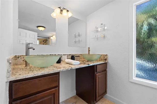 a bathroom with a granite countertop sink and a mirror