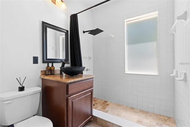 a bathroom with a granite countertop sink toilet and mirror