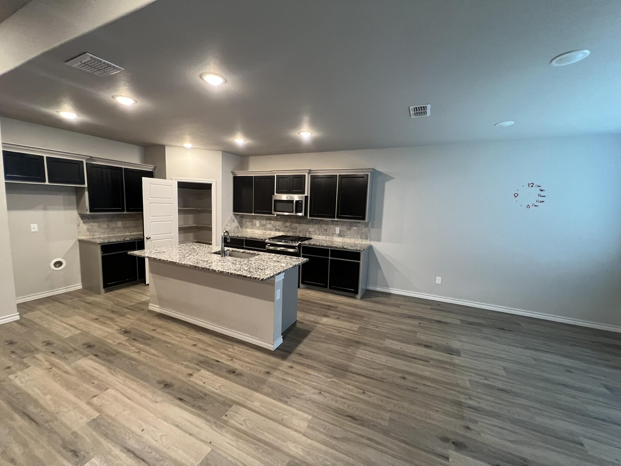 816 North 3rd Street Wolfforth, TX 79382 - Photo 8 of 28 a large kitchen with kitchen island granite countertop a stove top oven a sink dishwasher a dining table and chairs with wooden floor