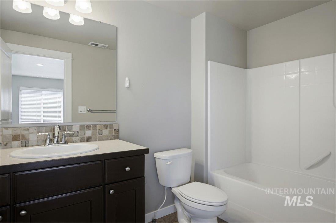 12460 West Azure Street Boise, ID 83713 - Photo 22 of 34 Bathroom featuring a dark wood-finish vanity with a light countertop, a rectangular sink with chrome fixtures, and a mosaic tile backsplash