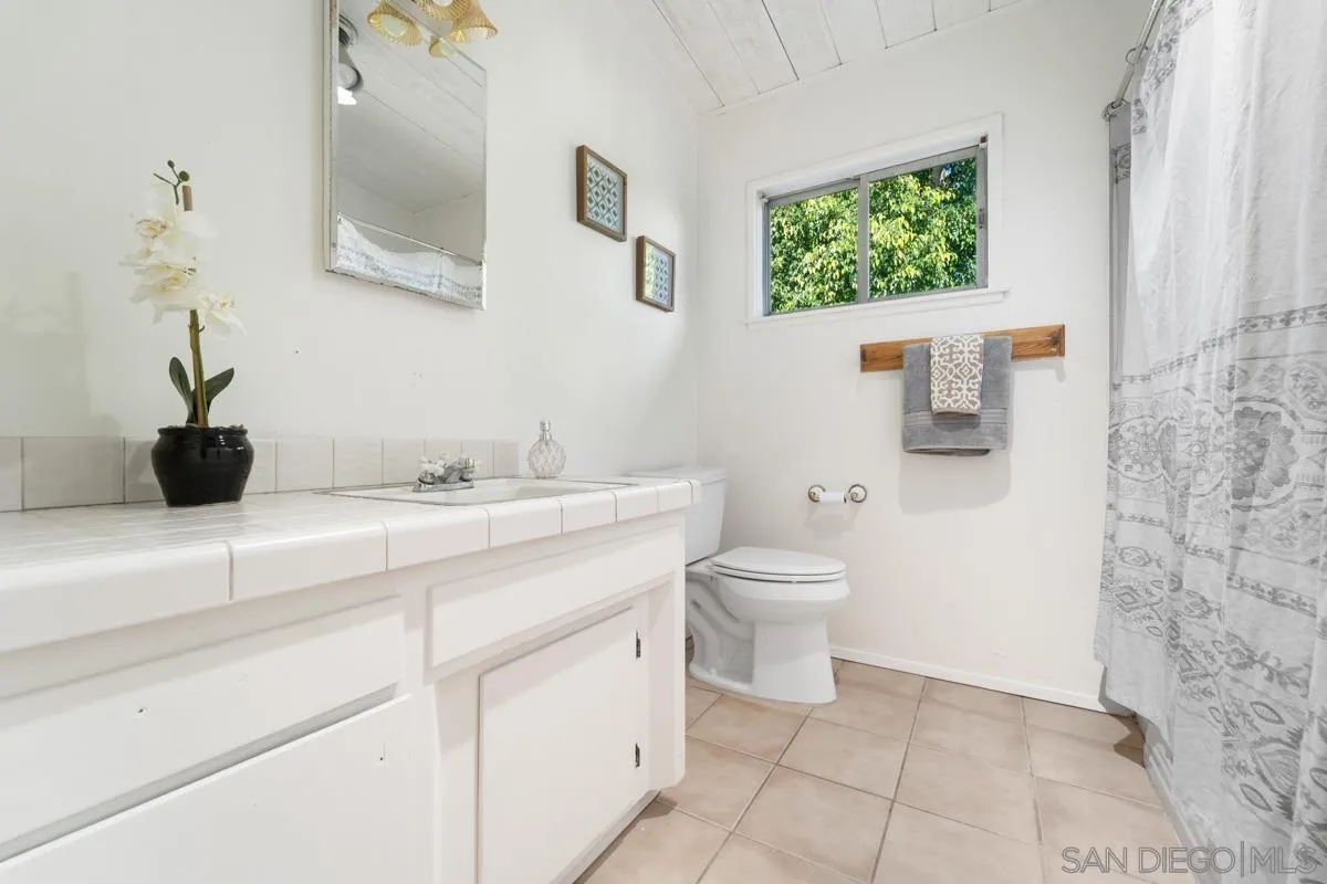 4276 Orchard Drive Spring Valley, CA 91977 - Photo 10 of 19 a bathroom with a granite countertop sink a toilet and a mirror