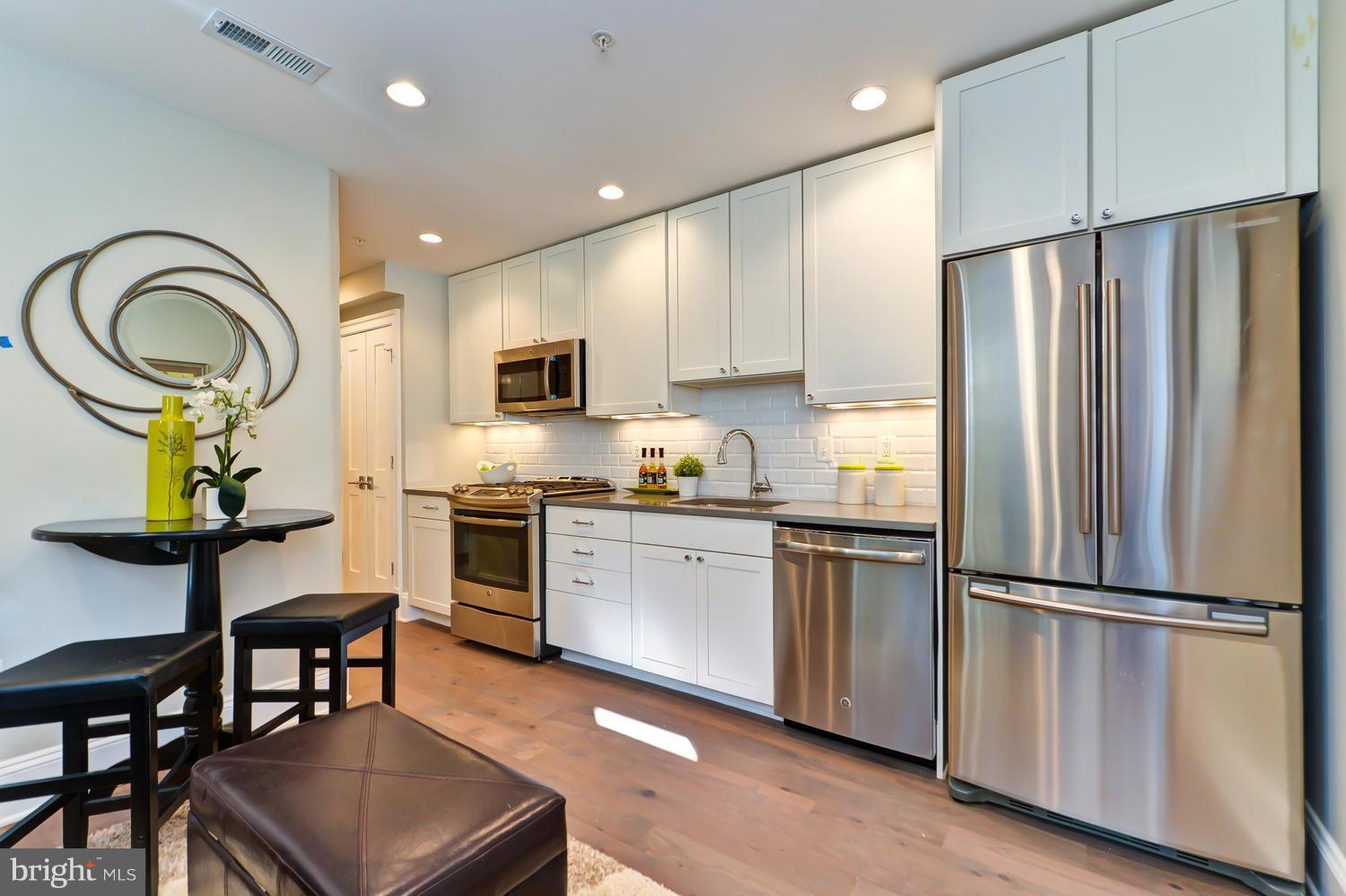 3921 Fulton Street Northwest, Unit 1 Washington, DC 20007 - Photo 4 of 25 a kitchen with stainless steel appliances granite countertop a refrigerator a stove a sink a dining table and chairs
