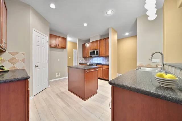 a kitchen with stainless steel appliances granite countertop wooden cabinets a stove top oven a sink and dishwasher