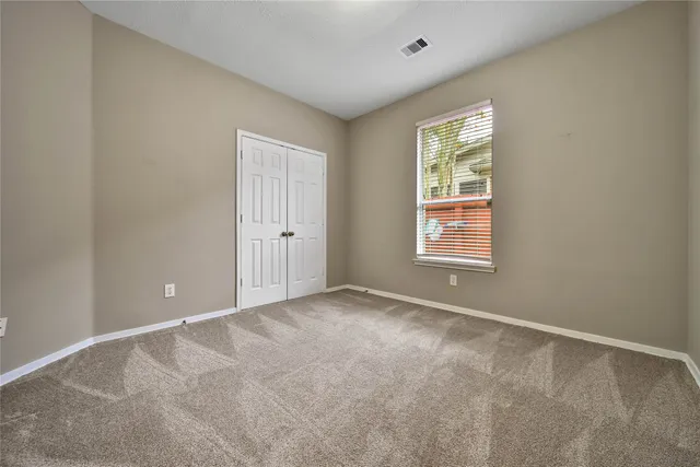 a view of an empty room with window and ceiling fan