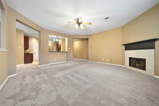 an empty room with windows and fireplace ceiling fan