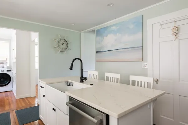 a kitchen with stainless steel appliances a white refrigerator a sink a stove and white cabinets with wooden floor