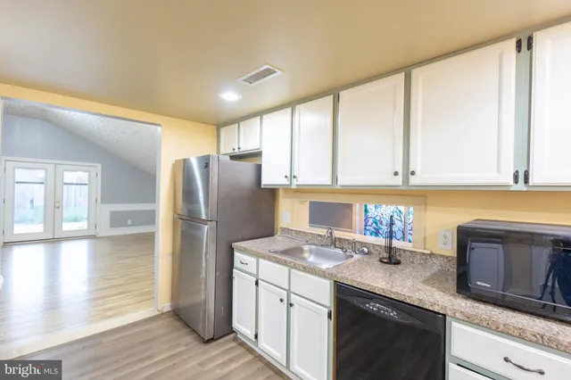 a large kitchen with stainless steel appliances granite countertop a refrigerator a stove and a sink with cabinets