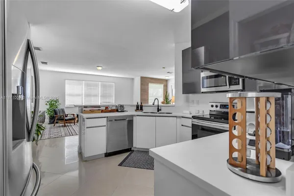 a living room with furniture wooden floor and a kitchen view