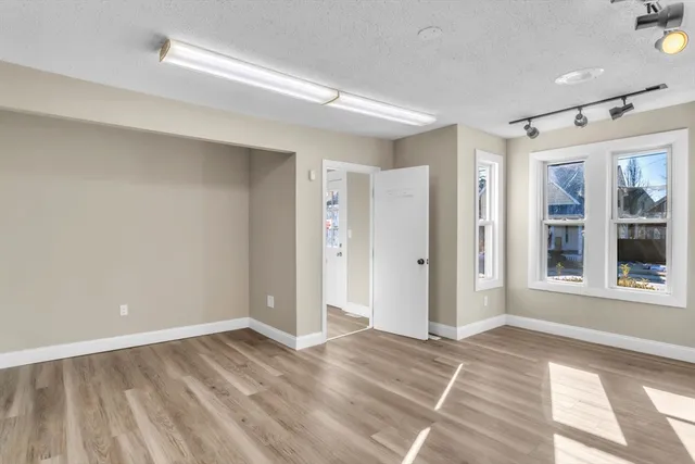 a view of an empty room with wooden floor and a window