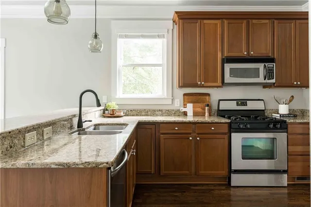 a kitchen with stainless steel appliances granite countertop a stove a sink and a microwave