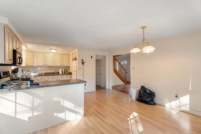 a kitchen with stainless steel appliances granite countertop a sink dishwasher a stove and a refrigerator with wooden floor