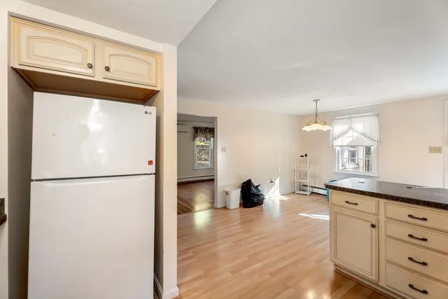 a kitchen with refrigerator a stove a sink and white cabinets with wooden floor