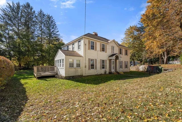 a white house with a small yard and large trees