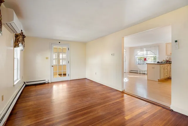 an empty room with wooden floor and a kitchen