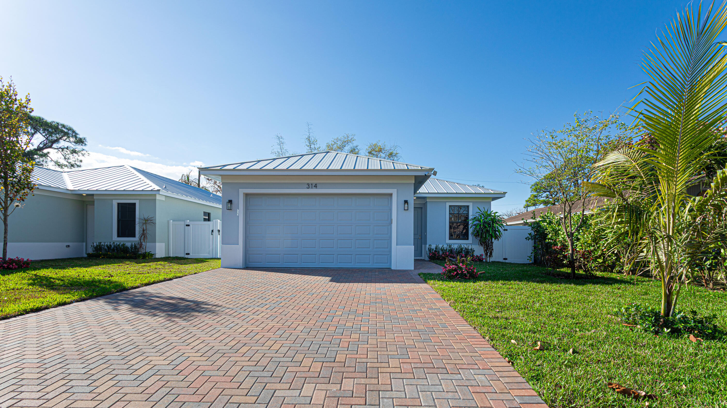 314 4th Street Jupiter, FL 33458 - Photo 3 of 55 a front view of a house with a yard and garage