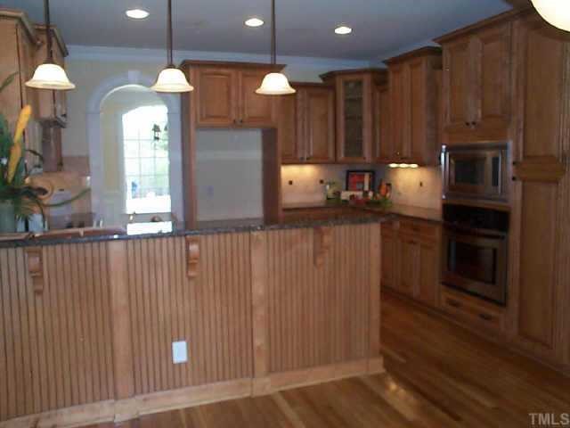 4200 Cypress Ridge Court Raleigh, NC 27616 - Photo 3 of 10 a kitchen with kitchen island granite countertop wooden cabinets a stove and a window