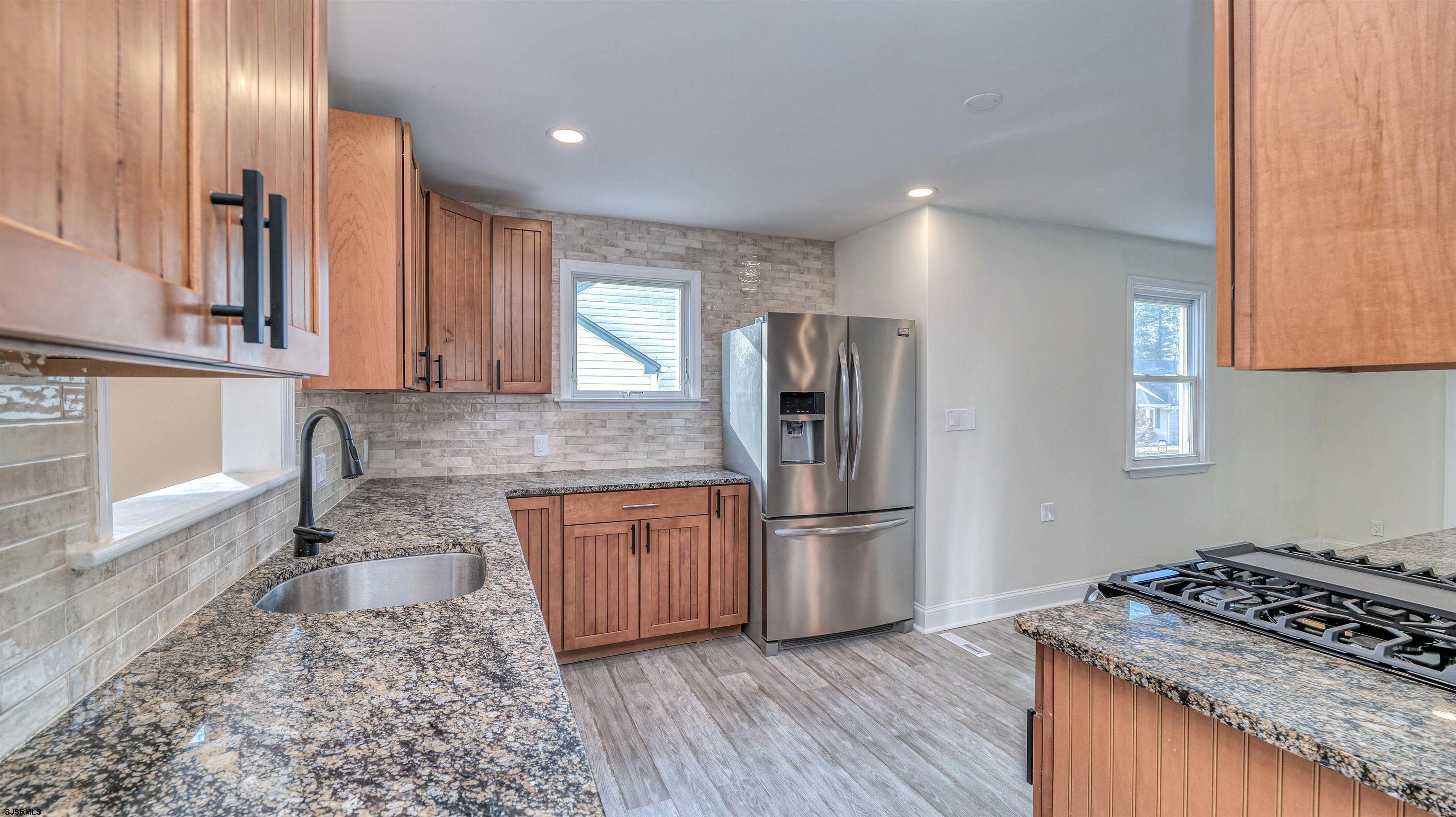 130 Davis Avenue Absecon, NJ 08201 - Photo 14 of 38 a kitchen with granite countertop stainless steel appliances a refrigerator cabinets and wooden floor