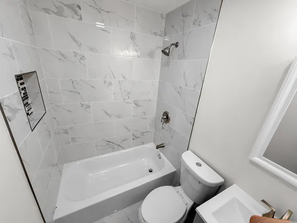 a bathroom with a bathtub shower sink vanity and toilet
