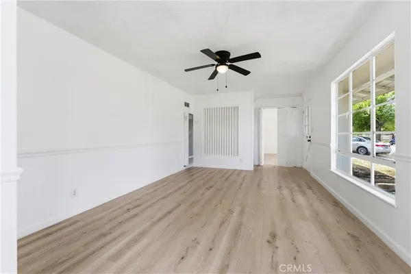 a view of empty room with wooden floor and fan