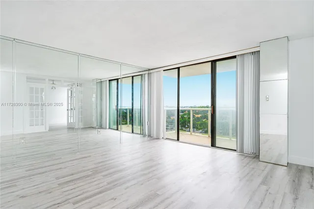 a view of an empty room with wooden floor and a glass door