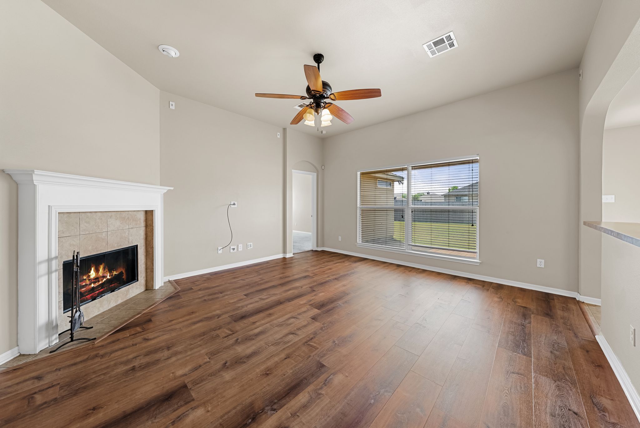 7719 Fieldstone Drive Temple, TX 76502 - Photo 12 of 37 Unfurnished living room with dark wood-type flooring, ceiling fan, a tile fireplace, and arched walkways