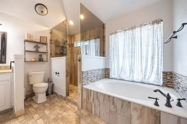 a bathroom with a granite countertop sink a toilet a mirror and shower
