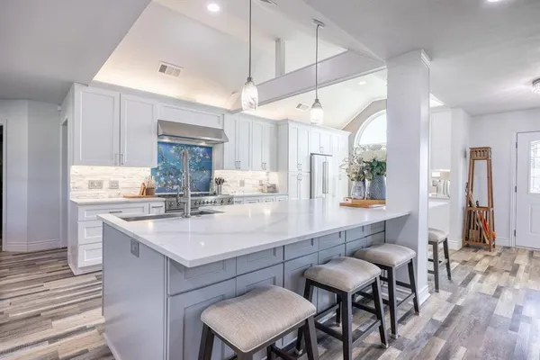 a large kitchen with sink a counter space appliances and cabinets