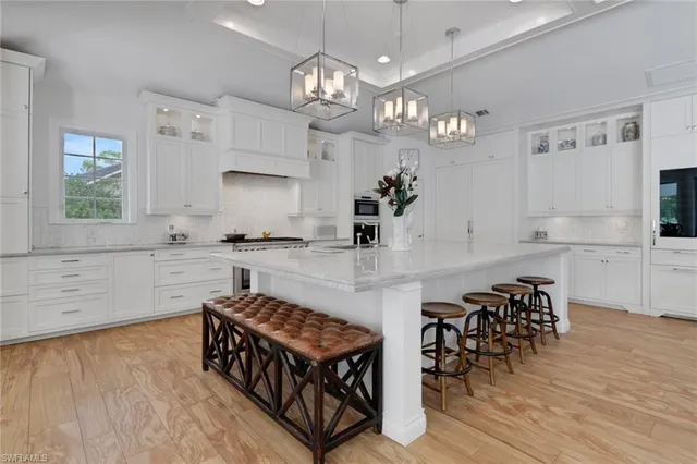 a kitchen with stainless steel appliances granite countertop a stove top oven a sink dishwasher and white cabinets with wooden floor