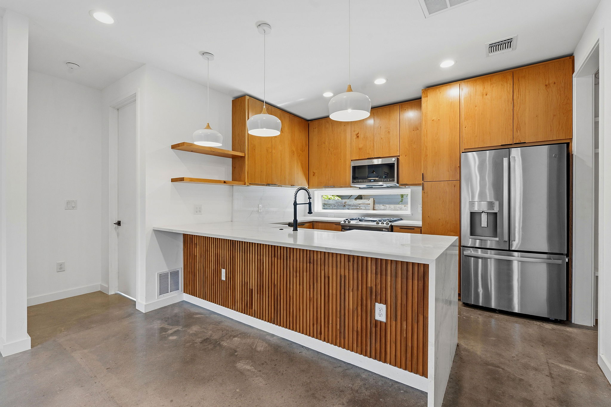 1707 Deloney Street, Unit 2 Austin, TX 78721 - Photo 9 of 26 A sleek island with modern pendant lights anchors this functional kitchen space.