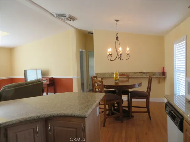 a dining room with furniture a chandelier and kitchen view