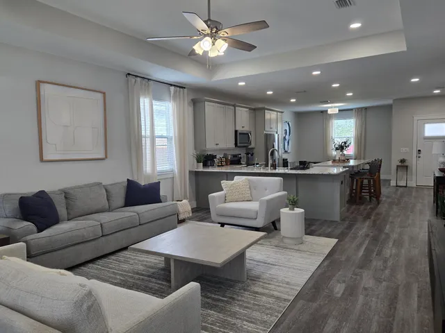 a living room with furniture kitchen view and a wooden floor