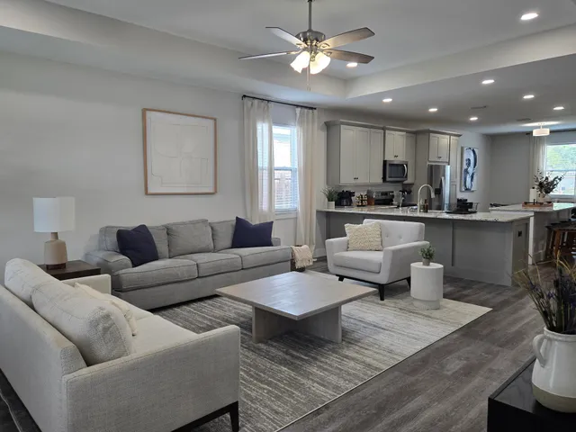 a living room with furniture kitchen view and a chandelier