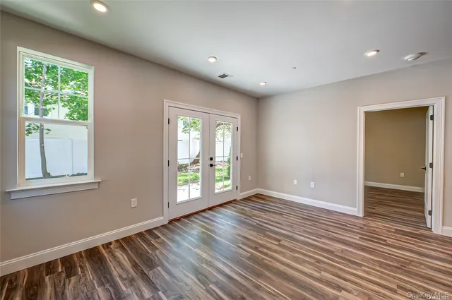 an empty room with wooden floor and windows