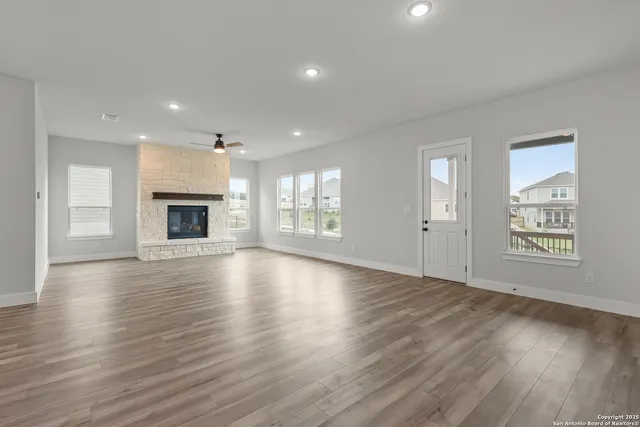 an empty room with wooden floor fireplace and windows
