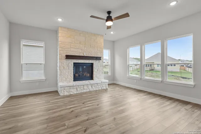 an empty room with wooden floor fireplace cabinet and windows