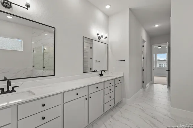 a spacious bathroom with double vanity a mirror and a shower