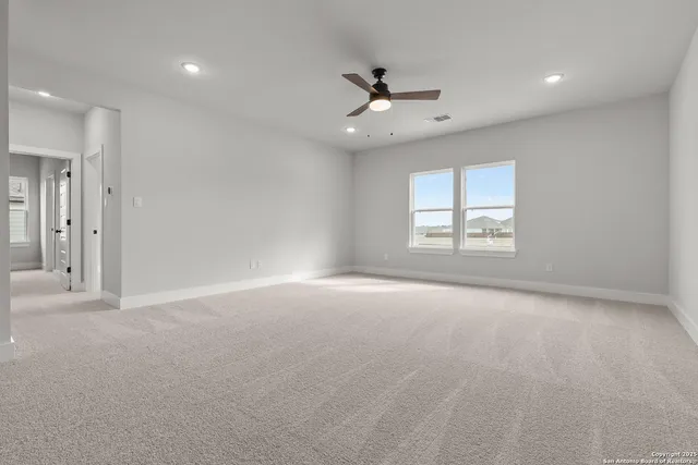 an empty room with windows and ceiling fan