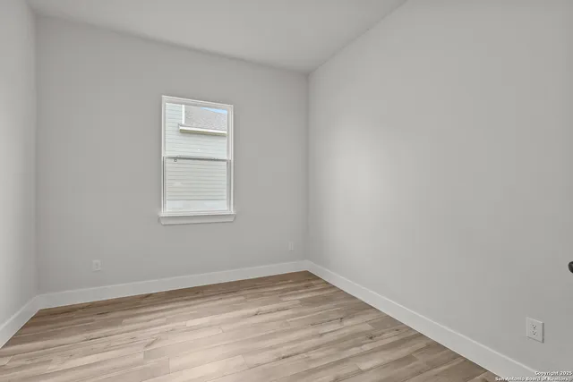 a view of a room that has wooden floor and window in it