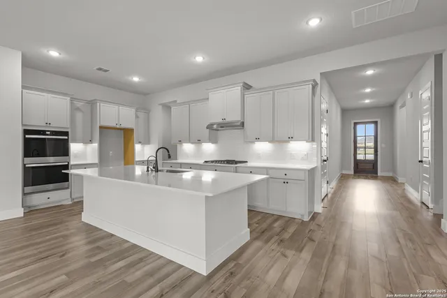 a large kitchen with cabinets wooden floor and stainless steel appliances