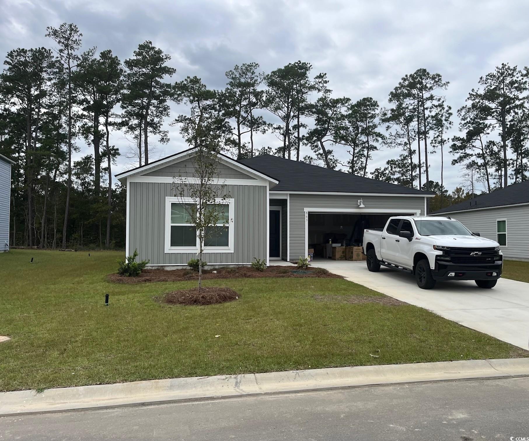 Ranch-style home featuring board and batten siding, concrete driveway, a front lawn, and an attached garage