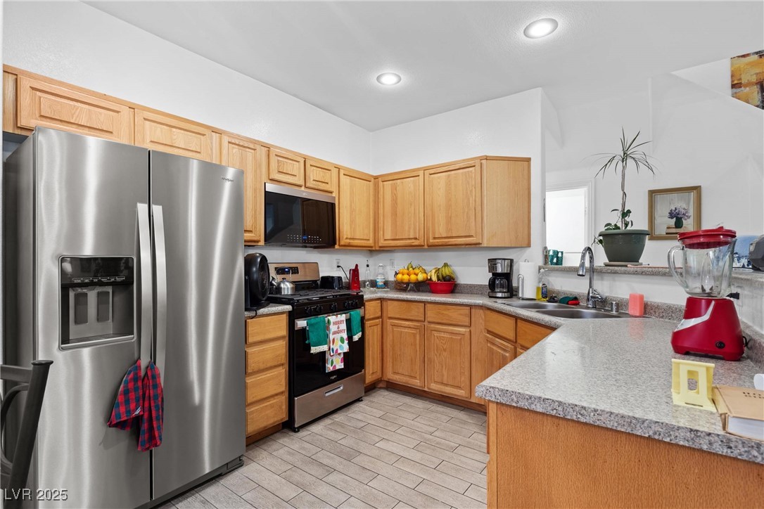 1289 Large Cap Drive, Unit 2 Henderson, NV 89074 - Photo 27 of 32 Kitchen featuring appliances with stainless steel finishes, light countertops, wood finish floors, recessed lighting, and light brown cabinetry