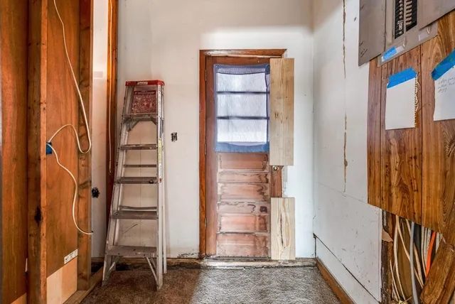 an empty room with a chandelier fan and windows