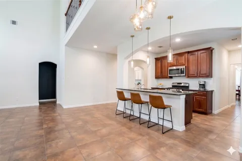 a large kitchen with granite countertop a stove a sink a counter space and cabinets